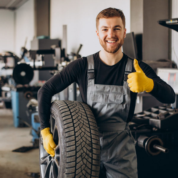 Car mechanic changing wheels in car